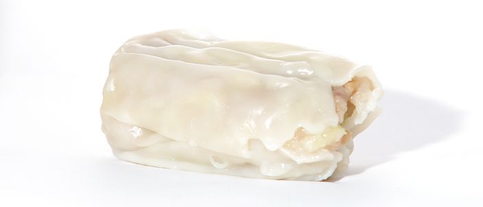 A single steamed dim sim, a plump wheat-wrapped dumpling with a slightly translucent pale skin, photographed on a white background.