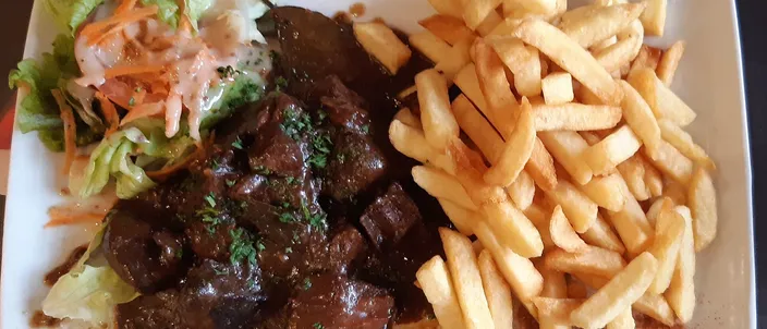 A plate of dark beef-and-beer stew served with a portion of fries and a little salad