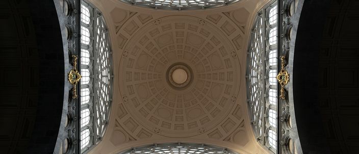 Looking straight up into the coffered stone-and-plaster dome over the main hall of Antwerpen-Centraal station, a circular oculus at its centre and tall arched windows filling the four sides.