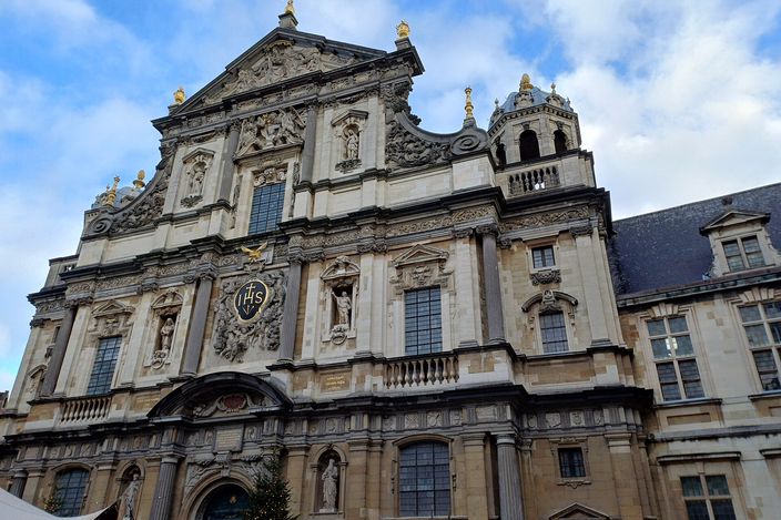 The white Baroque facade of the Sint-Carolus Borromeuskerk rising over Hendrik Conscienceplein, its three tiers of pilasters and central bell gable in full sun.