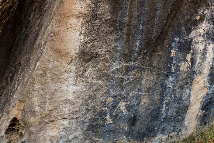 A carved animal figure etched into a dark, weathered rock face at Gobustan, one of the reserve's ancient petroglyphs.