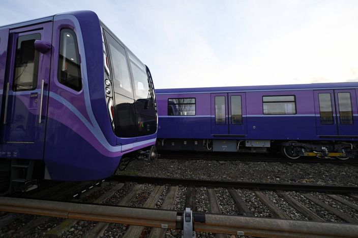 Two of Baku Metro's new purple rolling-stock trains standing on outdoor depot tracks, the lead car's front end facing the camera.