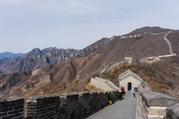 The Great Wall at Mutianyu running along a wooded ridge, watchtowers spaced along it and mountains receding behind