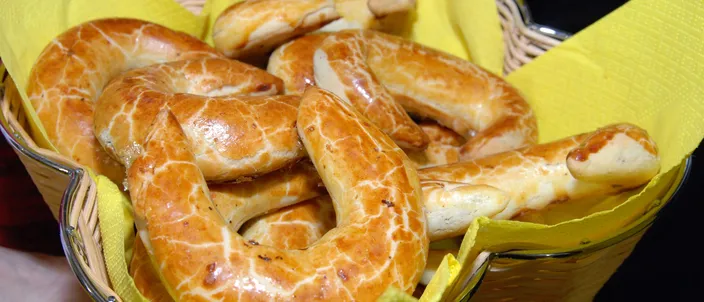 A basket lined with a yellow napkin holding several crescent-shaped Bratislava rolls, their glazed surfaces showing the characteristic pale marbled crackle over glossy brown.