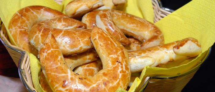 A basket lined with a yellow napkin holding several crescent-shaped Bratislava rolls, their glazed surfaces showing the characteristic pale marbled crackle over glossy brown.