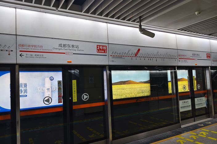 Platform screen doors at Chengdu East Railway Station on Metro Line 2, with bilingual station signage 'Chengdu East Railway Station' and a route strip map above the doors, a train visible through the glass.