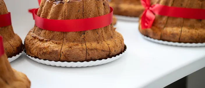 Savory kougelhopfs tied with red ribbons on a white counter, their fluted, nut-studded crusts dark gold