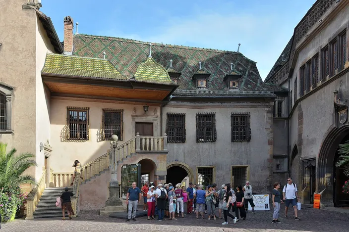 Visitors gathered before the Koïfhus, Colmar's old customs house, with its outside stair, balcony and green-and-gold glazed tile roof