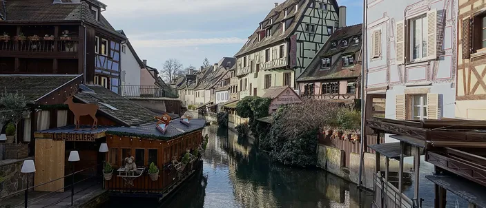 The Lauch in Petite Venise, Colmar, between half-timbered houses and wooden waterside terraces under a winter sky
