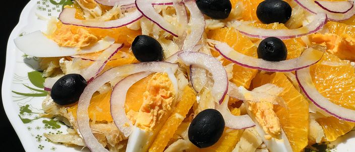 A plate of remojón: slices of orange with flaked salt cod, rings of red onion, black olives and wedges of boiled egg.