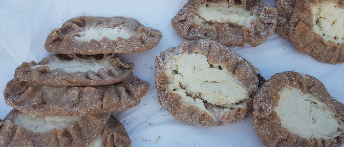 Several Karelian rice pies with thin dark rye crusts pinched into fluted rims around pale rice filling.