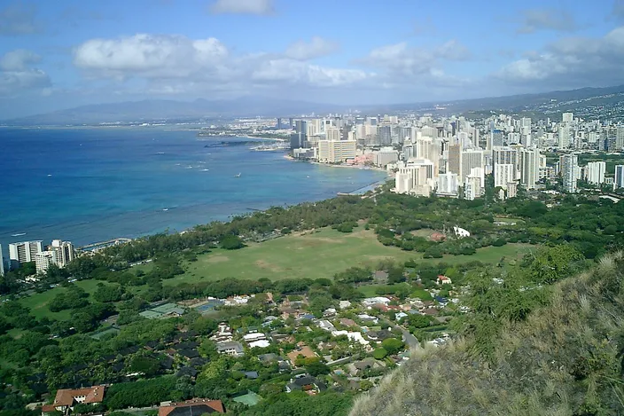 View from the rim of Diamond Head over the green lawns of Kapiʻolani Park to the hotel towers of Waikīkī and the coast beyond