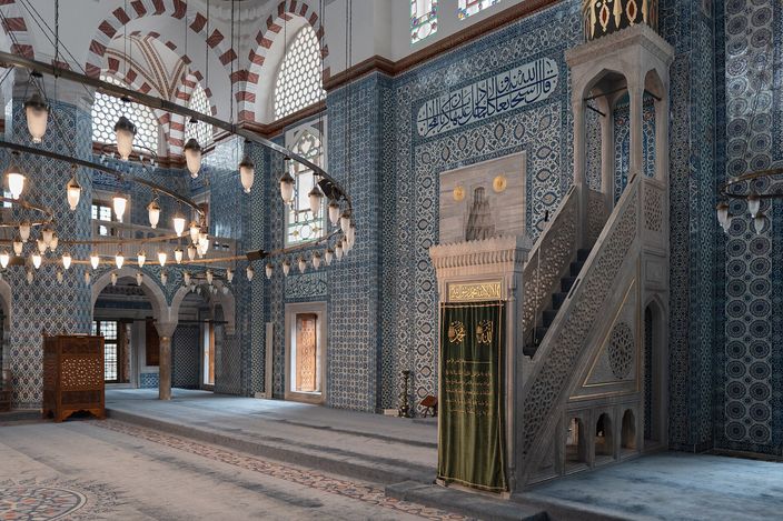The tiled interior of the Rüstem Pasha Mosque: İznik panels in blue and red covering the walls and piers around a slender white minbar
