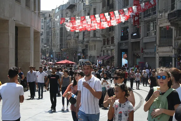 İstiklal Avenue full of people walking between its tall nineteenth-century frontages, bunting strung overhead