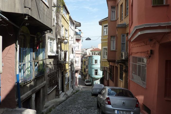 A steep cobbled lane in Fener climbing between tall wooden houses painted in different colours