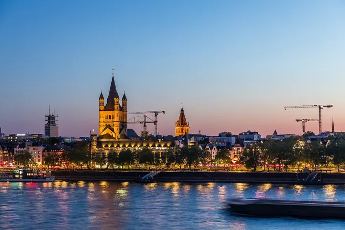 Great St. Martin's tower, the town hall tower and the gabled houses of the Fischmarkt lit at blue hour, seen across the Rhine