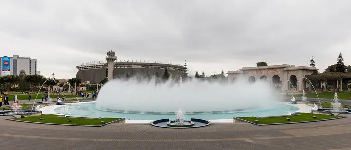 The great circular fountain of Lima's Circuito Magico del Agua throwing a wide ring of mist, paths and lawns around it under an overcast sky.