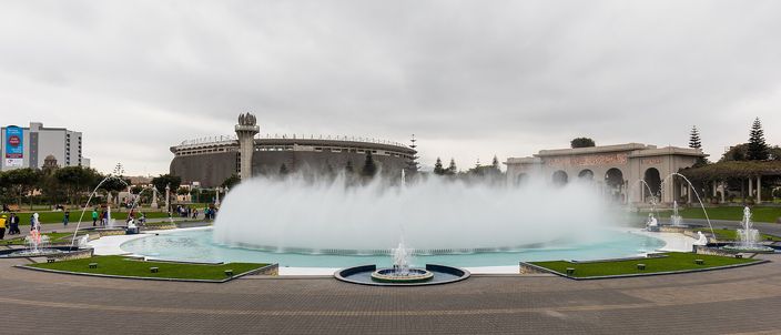 The great circular fountain of Lima's Circuito Magico del Agua throwing a wide ring of mist, paths and lawns around it under an overcast sky.