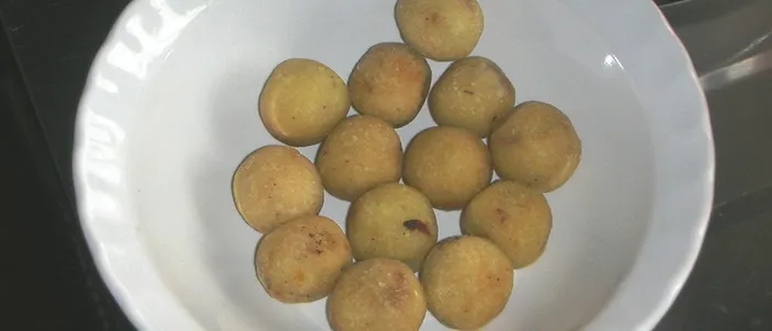 A white bowl holding a dozen gulha — small round deep-fried balls with a golden crust — one of the classic Maldivian short eats.