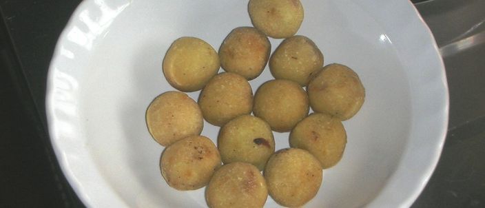 A white bowl holding a dozen gulha — small round deep-fried balls with a golden crust — one of the classic Maldivian short eats.