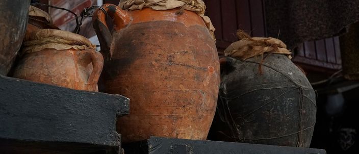 Several tall unglazed terracotta tangia urns with rope-tied mouths standing together in a Marrakesh souk setting