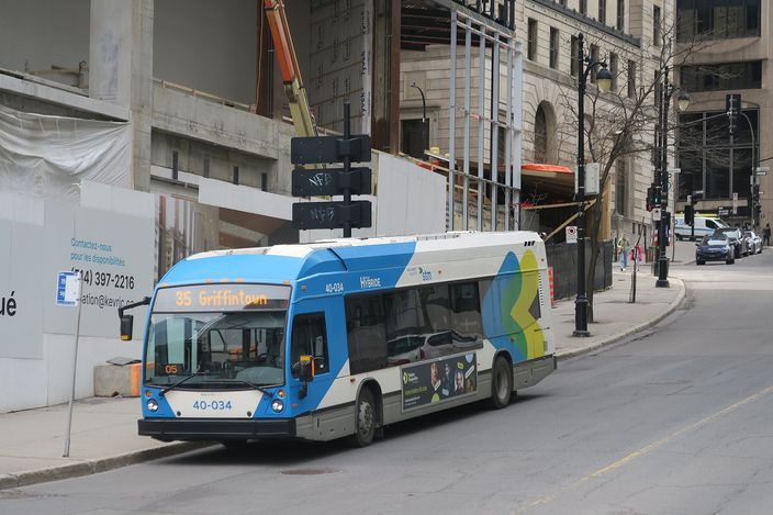 An STM city bus in blue, white and green livery, route 35 to Griffintown, on a downtown Montréal street lined with stone buildings