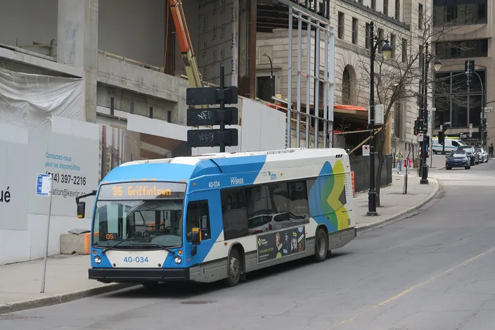 An STM city bus in blue, white and green livery, route 35 to Griffintown, on a downtown Montréal street lined with stone buildings