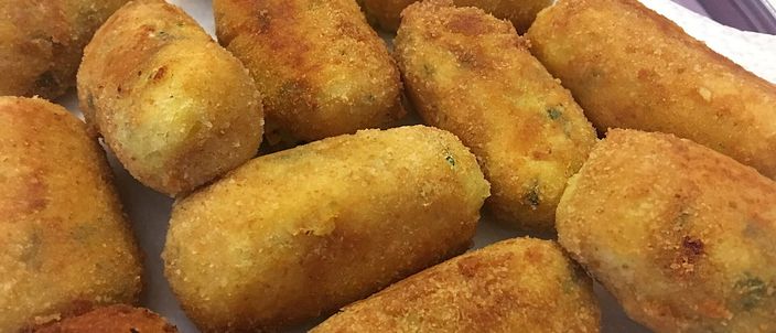 A plate piled with golden-brown fried crocchè, the elongated breaded potato croquettes flecked with parsley
