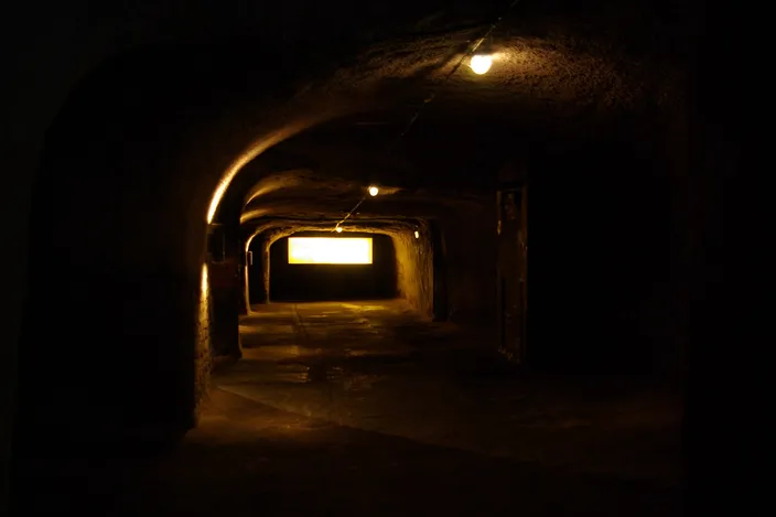 A lamp-lit tunnel cut into the sandstone of the Felsengänge, the rock cellars under Nuremberg's old town