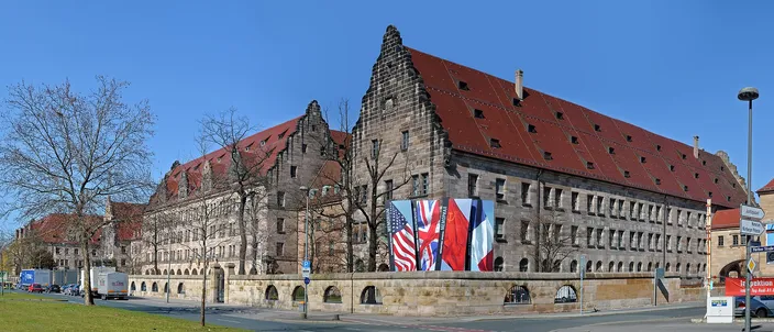 The long sandstone Palace of Justice in Nuremberg with its stepped gables and red roof, the flags of the four Allied powers hung on its corner