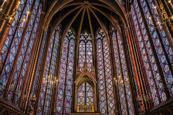 The upper chapel of the Sainte-Chapelle: walls of thirteenth-century stained glass rising the full height between slender painted shafts, the apse windows deep blue and red around a carved canopy
