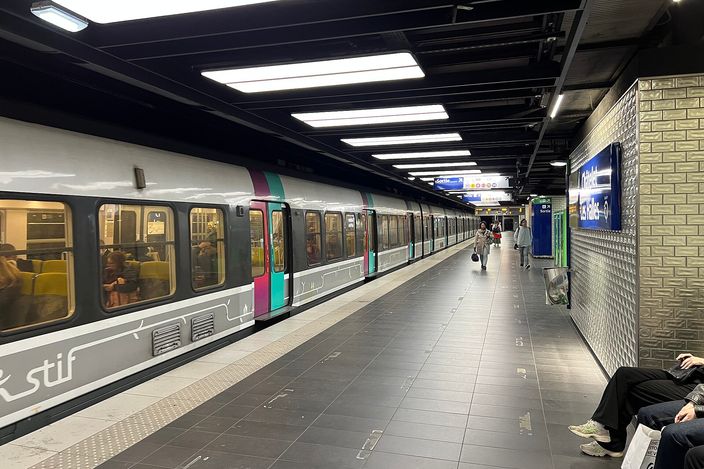 An RER B train at its underground platform at Châtelet–Les Halles, the older stock in Île-de-France livery stopped alongside a lit platform with a few waiting passengers