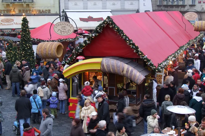 A red-roofed hut on Old Town Square selling trdelník, a giant model of the spit-rolled pastry over its counter and a sign calling it old-Czech, crowds of visitors around it