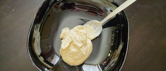 A spoonful of thick white skyr in a dark bowl, holding its shape on the spoon