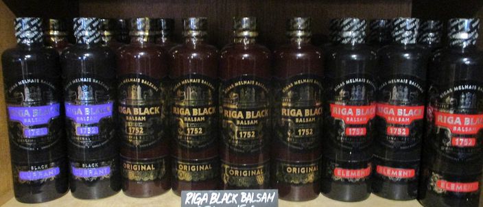 A row of Riga Black Balsam bottles on a shelf, the dark bottles labelled with the classic balsam and its variants.