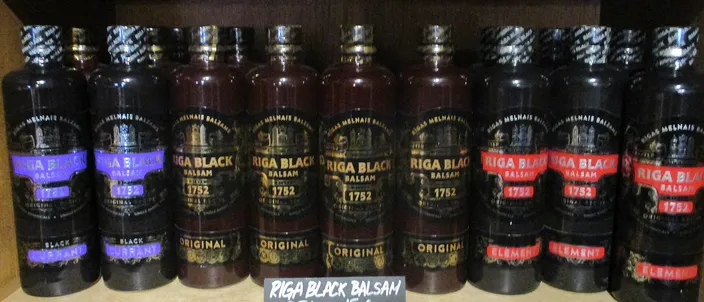 A row of Riga Black Balsam bottles on a shelf, the dark bottles labeled with the classic balsam and its variants.