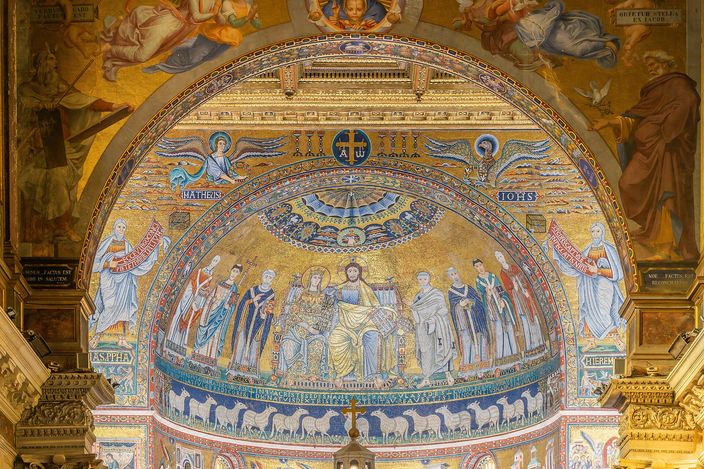 The apse mosaic of Santa Maria in Trastevere on a gold ground: Christ and the Virgin enthroned side by side beneath a jewelled arch, standing saints flanking them, and a band of white lambs processing along the wall below.