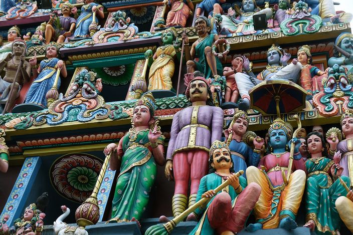 Tiers of brightly painted figures — gods, musicians and cows in green, pink and blue — crowded across the gate tower of the Sri Mariamman Temple