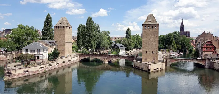 The Ponts Couverts towers standing in the still water of the Ill, with the cathedral spire rising behind the rooftops of Petite France