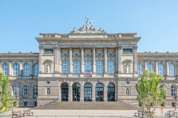 The Palais Universitaire in Strasbourg, a long sandstone front with a statue group on its central pediment, seen across its forecourt