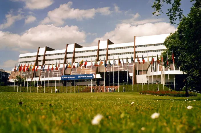The Palais de l'Europe, seat of the Council of Europe, behind its row of member-state flags on a lawn in Strasbourg's European Quarter.
