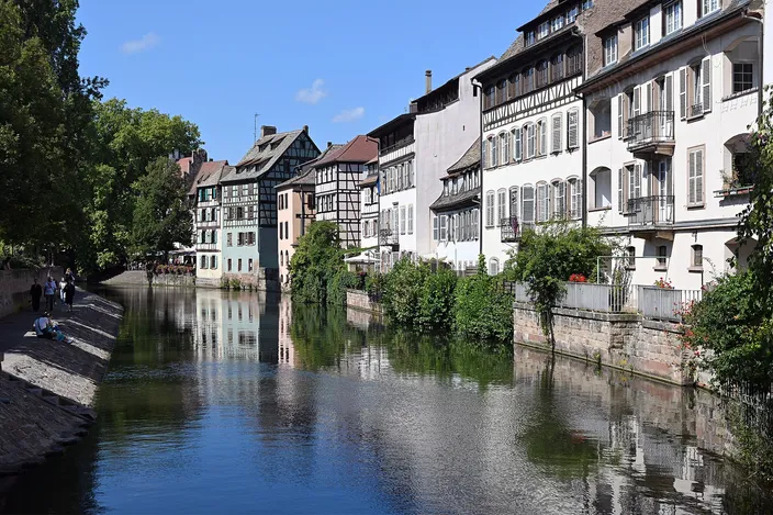 The Ill running between tall timber-framed and rendered houses in Petite France, seen westward from the Pont du Faisan