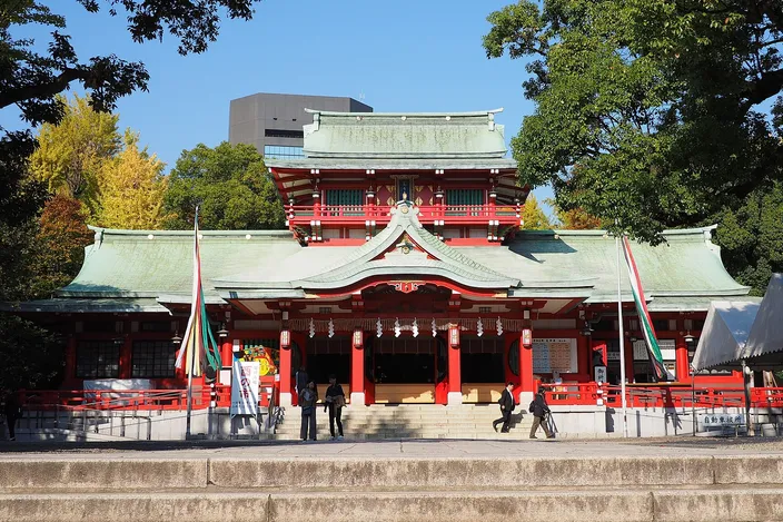 Tomioka Hachiman Shrine's vermilion and white hall at the top of its steps, with visitors crossing the forecourt