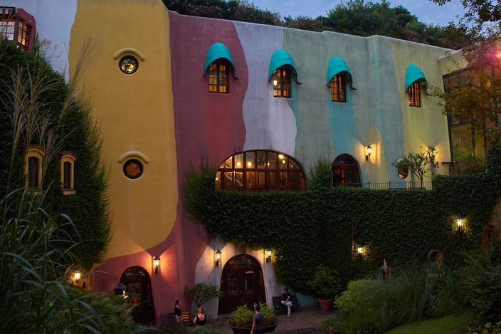 The Ghibli Museum's facade in ochre and green, its round windows and ivy-covered walls lit in the late afternoon