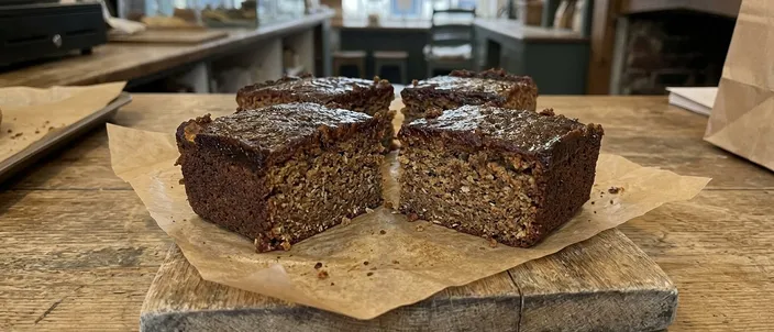 AI-generated image of squares of dark, sticky Yorkshire parkin on baking paper on a bakery counter
